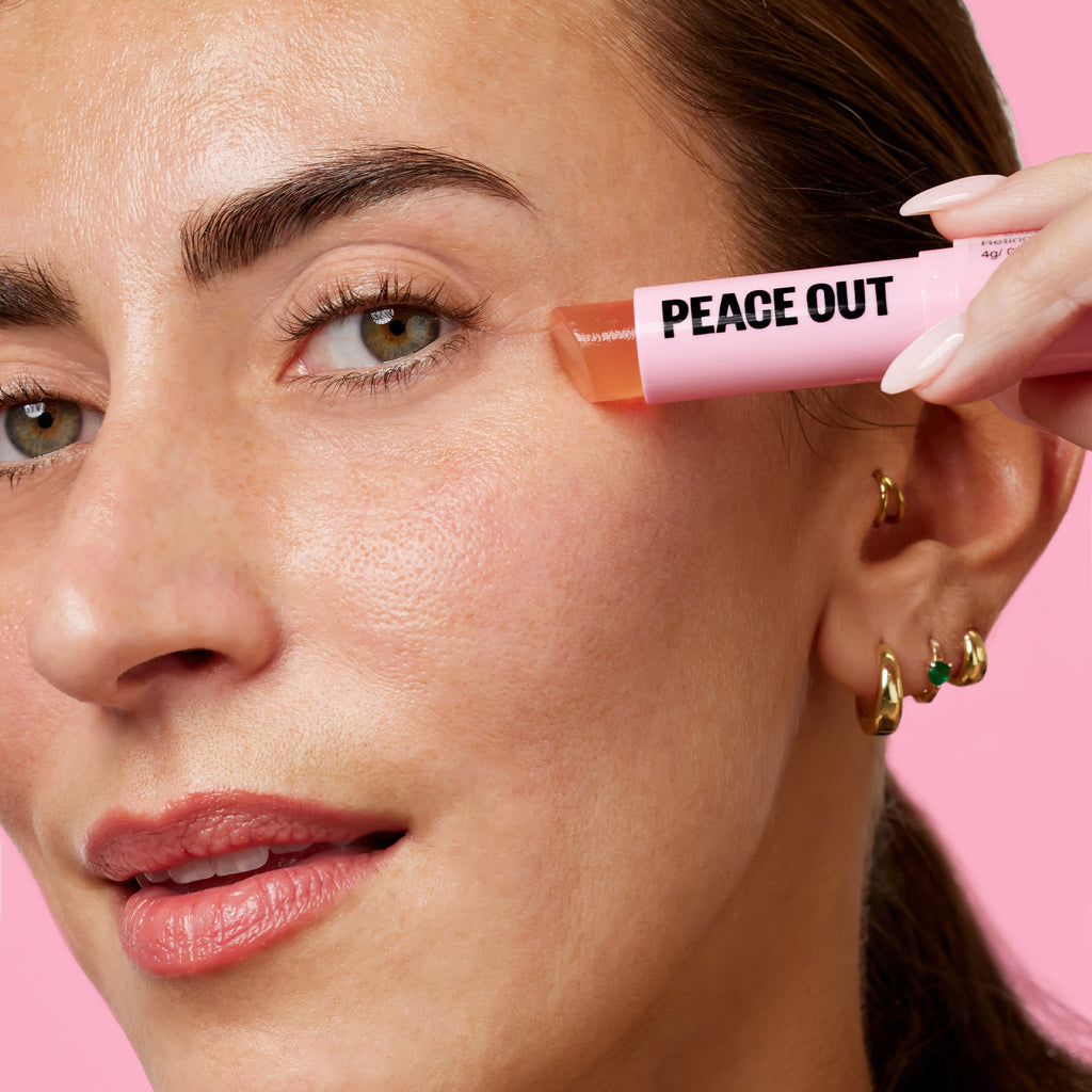 A woman with crow's feet applies Peace Out Retinol Eye Stick across her face