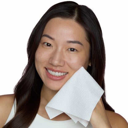 Woman with an antimicrobial silver-citrate-infused Silver Shield Face Towel by Peace Out on her face against a white background